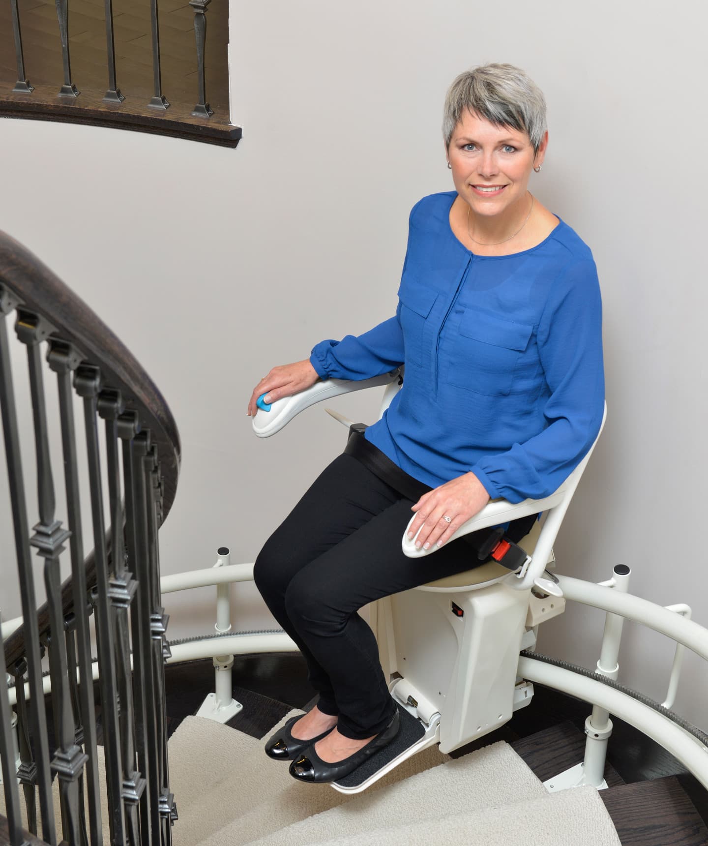 Woman on a Stairfriend stairlift riding up a set of curved stairs